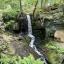 A waterfall cascading down mossy rocks next to the ruins of a mill
